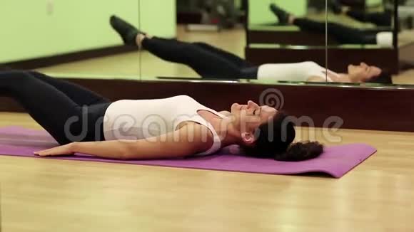 女人在健身房训练女人躺在垫子上抽着腹部肌肉视频的预览图
