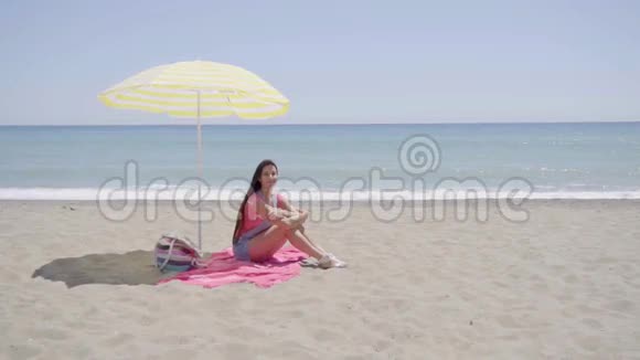 年轻女子在沙滩毛毯上挥舞着手视频的预览图