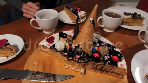 一片巧克力奶油布朗尼蛋糕上面有白巧克力和奶油花还有装饰有水果的热茶杯视频的预览图
