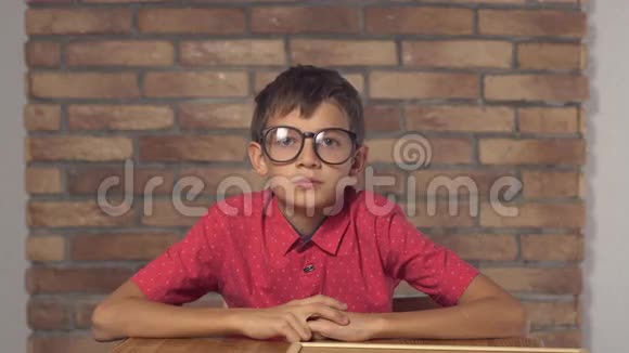 坐在书桌前的孩子拿着一张挂图上面有红色砖墙上的字母代码视频的预览图