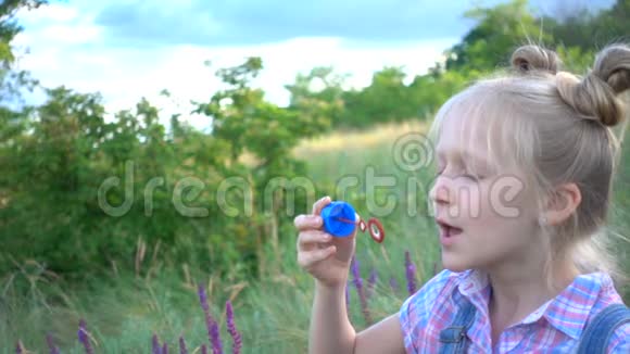 小女孩在绿色草坪上吹肥皂泡视频的预览图