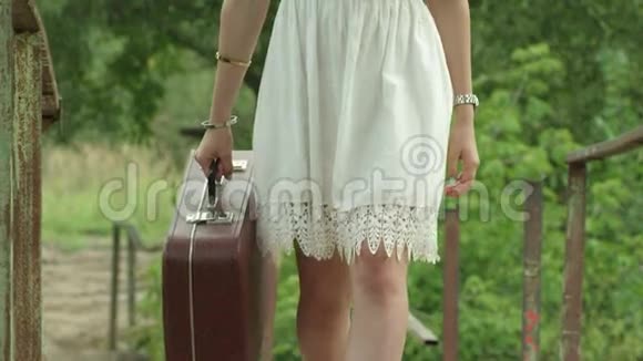 穿白色连衣裙的女孩提着棕色的手提箱慢动作视频的预览图