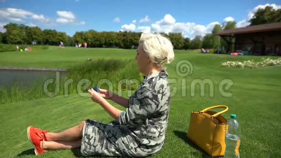 成熟的女人坐在绿草上视频的预览图