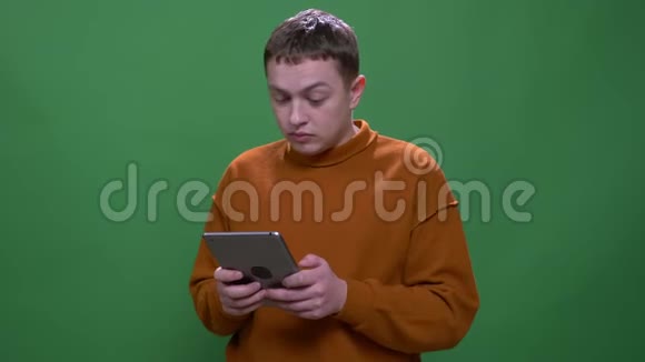 年轻有魅力的白种人男性的特写镜头使用的平板电脑背景隔离在绿色上视频的预览图