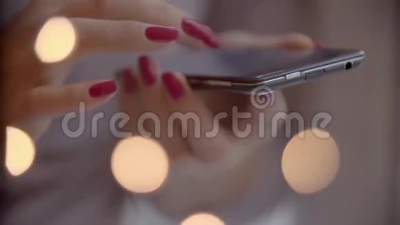 女人手使用手机智能手机有五颜六色的灯光背景特写镜头视频的预览图