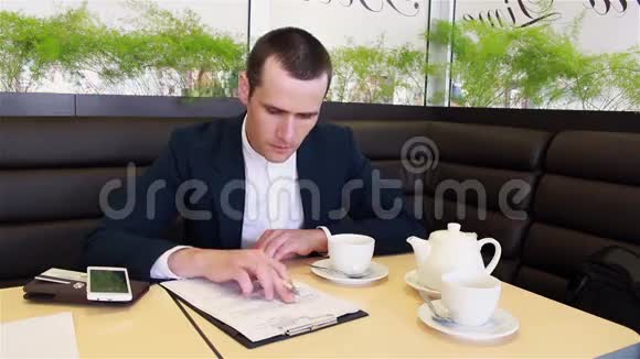 商人在一家咖啡馆里用智能手机记录数据视频的预览图