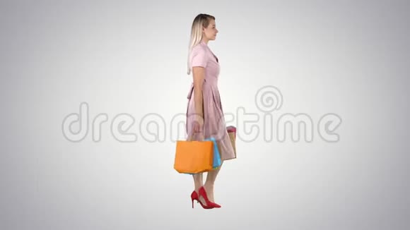 快乐的漂亮女孩拿着购物袋在梯度背景下散步视频的预览图