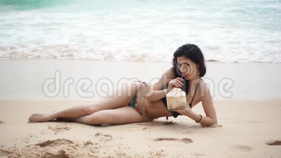 美丽的女孩躺在海滩上和椰子视频的预览图