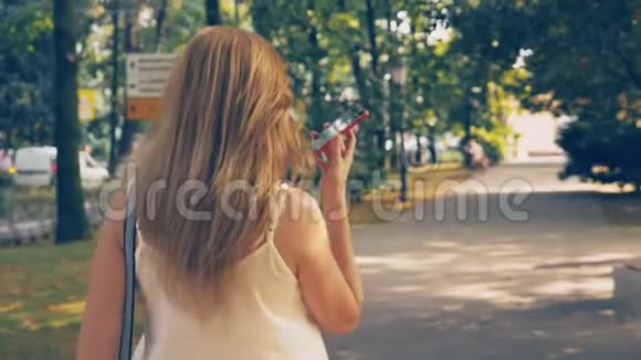 快乐的年轻女子在电话里交谈在炎热的阳光明媚的夏日沿着海滨散步4k慢动作视频的预览图