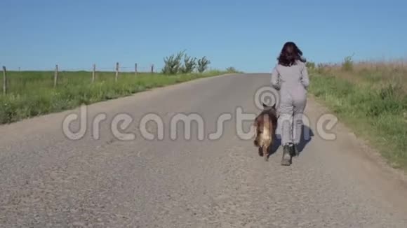 一个漂亮的女孩在路上牵着一只狗在她旁边视频的预览图
