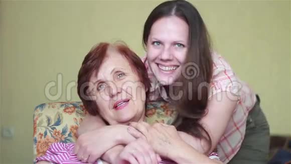 一位坐在椅子上抱着她的女孩的老妇人视频的预览图