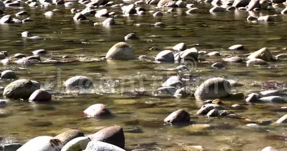 河水随着岩石和波浪缓缓流动视频的预览图