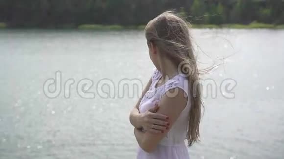 年轻美丽的少年女孩站在山湖附近的石头上特写视频的预览图