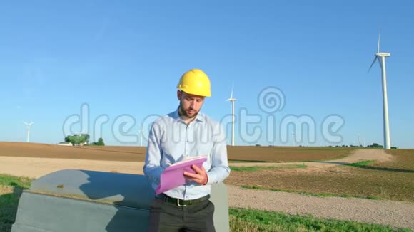 工程师坐在风车的背景上在图纸上做笔记视频的预览图