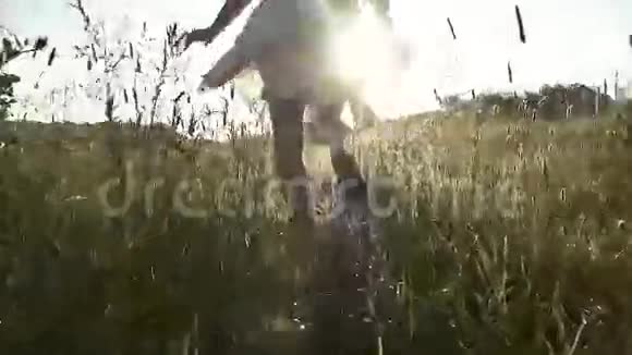 女孩嬉皮士在黎明时跑过草地洒下露水慢动作视频的预览图