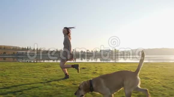 可爱的年轻女人和她可爱的狗在湖边的大自然中玩耍视频的预览图