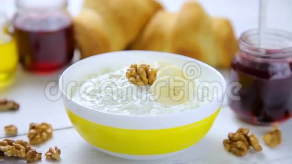 健康早餐酸奶油香蕉核桃牛角面包蜂蜜和林果果果果酱放在碗里视频的预览图