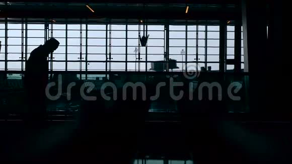 戴帽子的人在机场乘自动扶梯的剪影背景上的一个大窗口现代视频的预览图