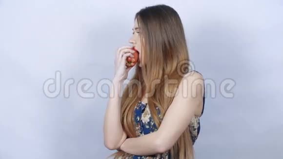 年轻的美女长发在灰色背景下吃苹果视频的预览图