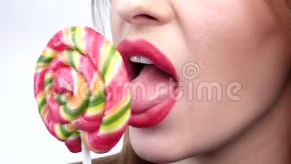 可爱的女人舔糖果与美丽的化妆隔离在白色背景特写视频的预览图