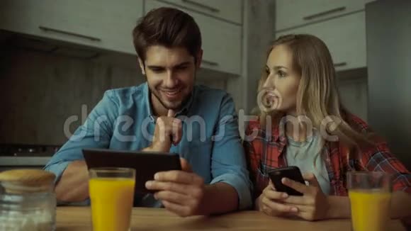 一对夫妇在家吃早餐时使用数码平板电脑视频的预览图