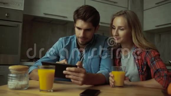 一对夫妇在家吃早餐时使用数码平板电脑视频的预览图