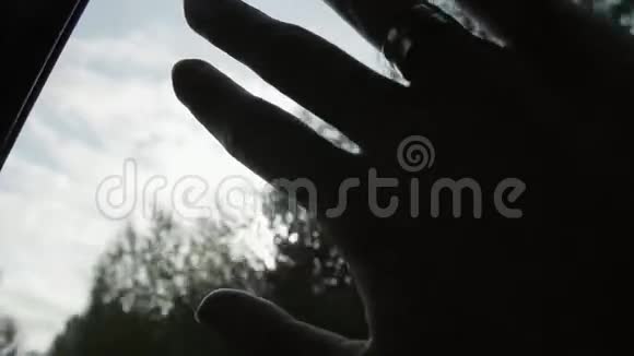 手的特写车窗上挂着戒指阳光透过手指和树木照耀手指掌慢节奏视频的预览图