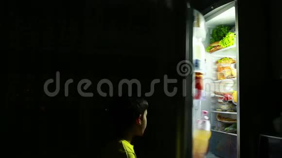 孩子半夜在冰箱前吃零食饥饿的男孩鸡翅视频的预览图