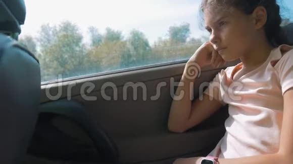 伤心的女孩无聊地坐在车后座上运动旅行小女孩在车里无聊概念生活方式视频的预览图