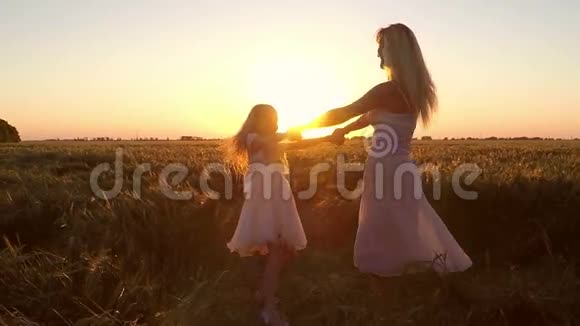 日落时分带着女孩的年轻女子在田野里转视频的预览图