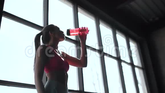把年轻女人的饮用水装在健身房里肌肉发达的女人在运动后休息20s4k视频的预览图
