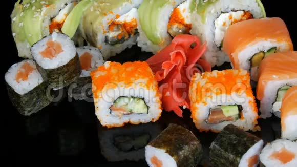 各种彩色寿司卷集和生姜旋转在镜面上的黑色背景日本料理视频的预览图
