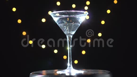 明亮的白色鸡尾酒在玻璃旋转在黑暗的背景与模糊的光视频的预览图