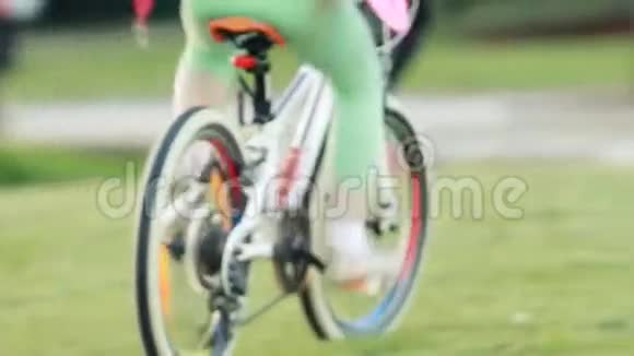 阳光明媚的日子里穿着运动服的小可爱女孩骑着自行车在城市公园里视频的预览图