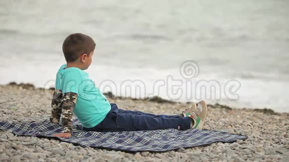 坐在海滩上的男孩视频的预览图