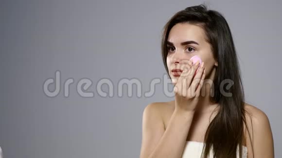 美容化妆品特写美丽的女人应用色调奶油基地在脸上有魅力的年轻女性肖像视频的预览图