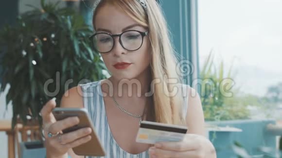 漂亮的女人用信用卡和手机购物女性在咖啡馆网上购物视频的预览图