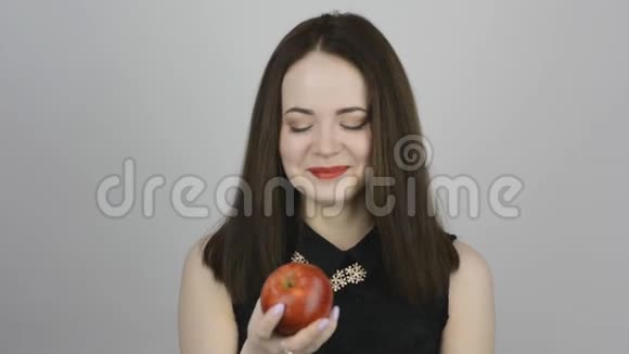 迷人的年轻女人吃着红苹果微笑着视频的预览图