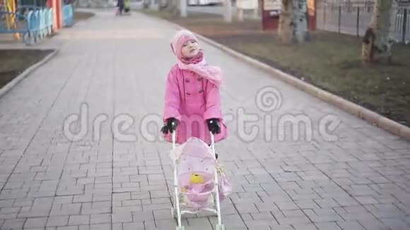 小女孩在公园里玩玩具婴儿车视频的预览图