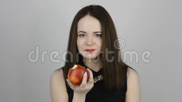 迷人的年轻女人吃着红苹果微笑着视频的预览图