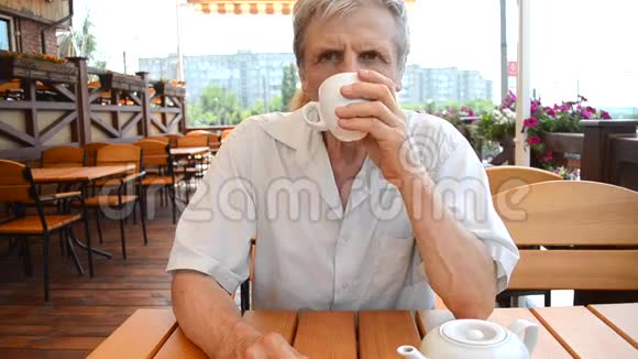 老人坐在桌子上在户外喝茶视频的预览图