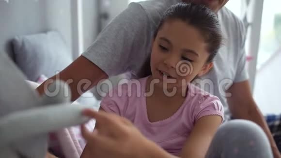 漂亮的小女孩和她父亲在卧室里休息视频的预览图