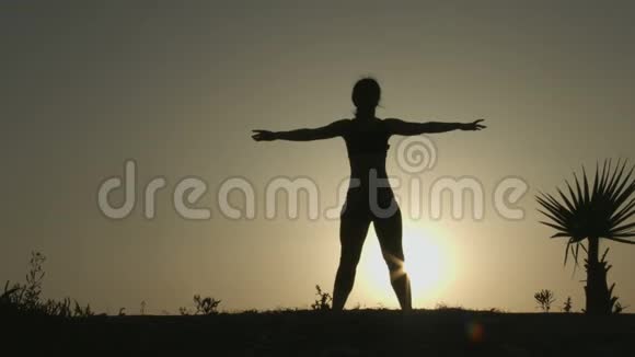 女性剪影做身体伸展运动在阳光下练习瑜伽视频的预览图