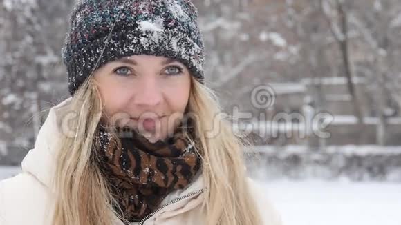 冬天的女孩在镜头前扔雪球微笑着在下雪的冬天在户外玩得开心视频的预览图