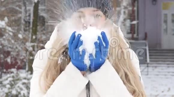 冬天快乐的女孩穿着冬天的衣服吹着雪高兴特写视频的预览图