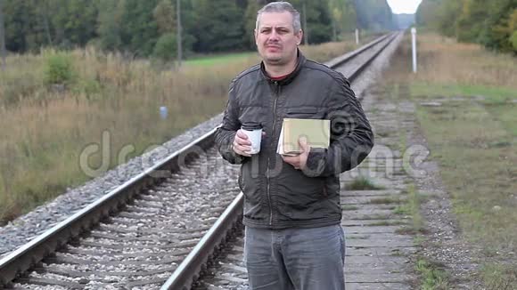 在铁路附近读书喝咖啡的男人视频的预览图