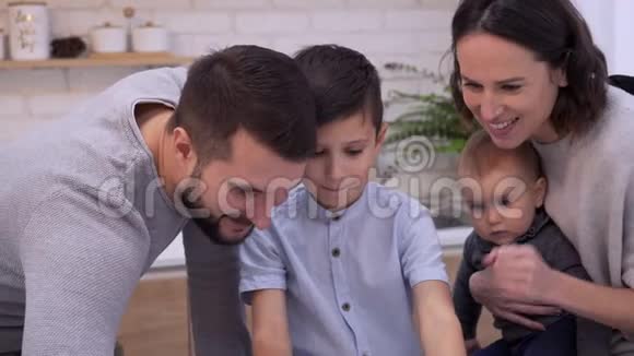 在数字平板电脑上与家人一起玩游戏的男孩视频的预览图