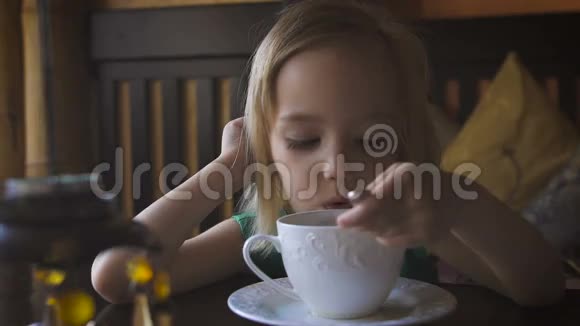 一个小孩在一家舒适的咖啡馆里吃早餐一个可爱的女孩喝茶享受早餐视频的预览图