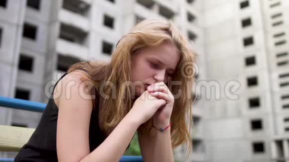 紧张的女孩坐在高楼附近视频的预览图