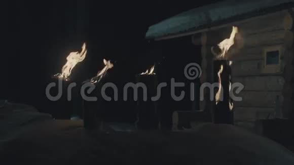 院子里燃烧的原木雪地里的小房子冬天的夜晚视频的预览图